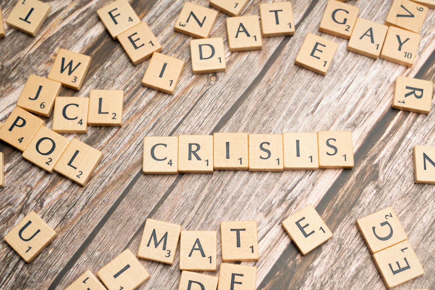 scrabble tiles spelling the word crissis on a wooden surface